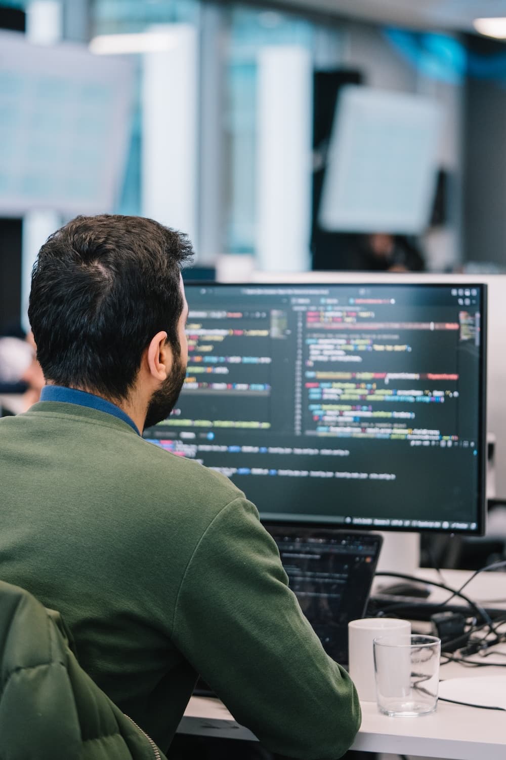 Engineer working with code across multiple desktop screens